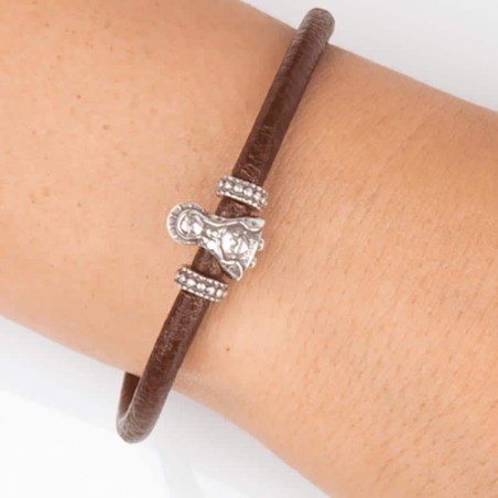 Pulsera cuero marrón con cierre mosquetón, con charm de Virgencita Niña en plata de primera ley. Muestra en muñeca.