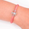 Pulsera de cordon de cabo rosa con cierre mosquetón. Con charm de Virgencita de la Milagrosa en plata de ley. Muestra en muñeca.
